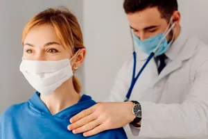 Médico com estetoscópio atende uma trabalhadora de máscara.